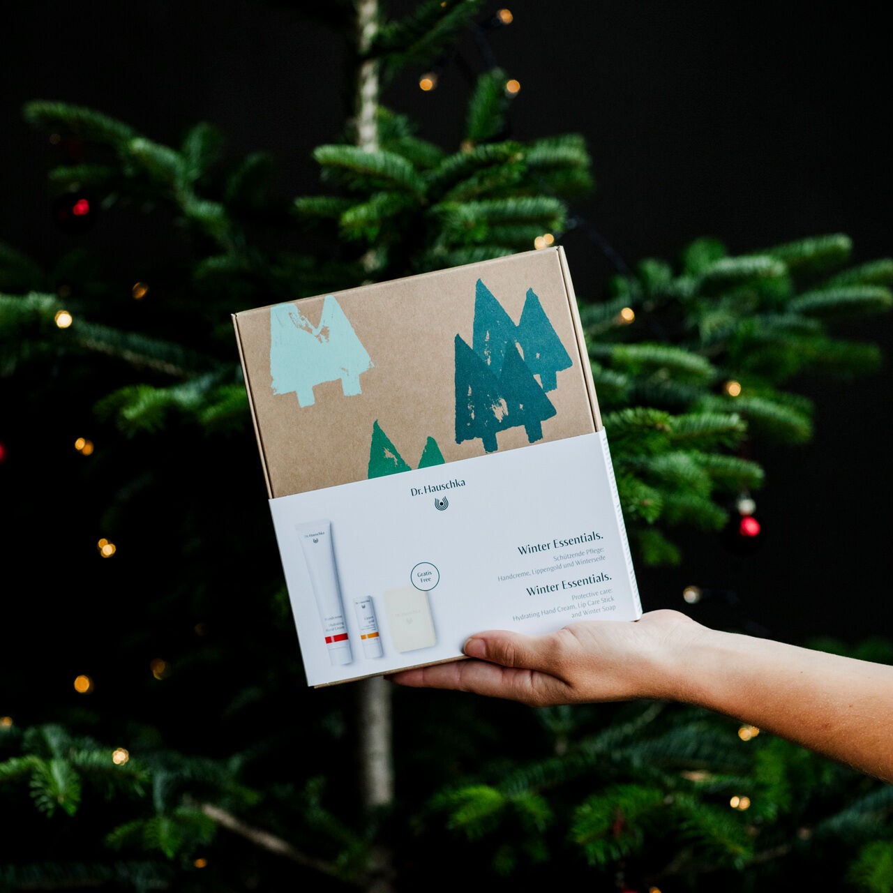 Weihnachten-2024-Geschenkset-Winter-Essentials-DE-GB-geschlossen-mit-Banderole-Hand-Model-Weiblich-Weihnachtsbaum_dic_master